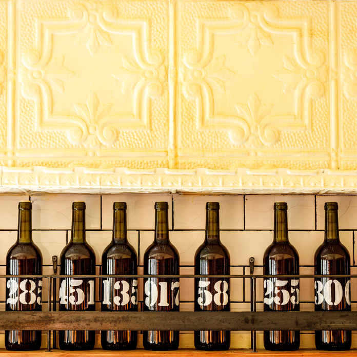 A bright, open-air restaurant with brick walls, hanging globe lights, and patrons dining under a wooden ceiling with fans.