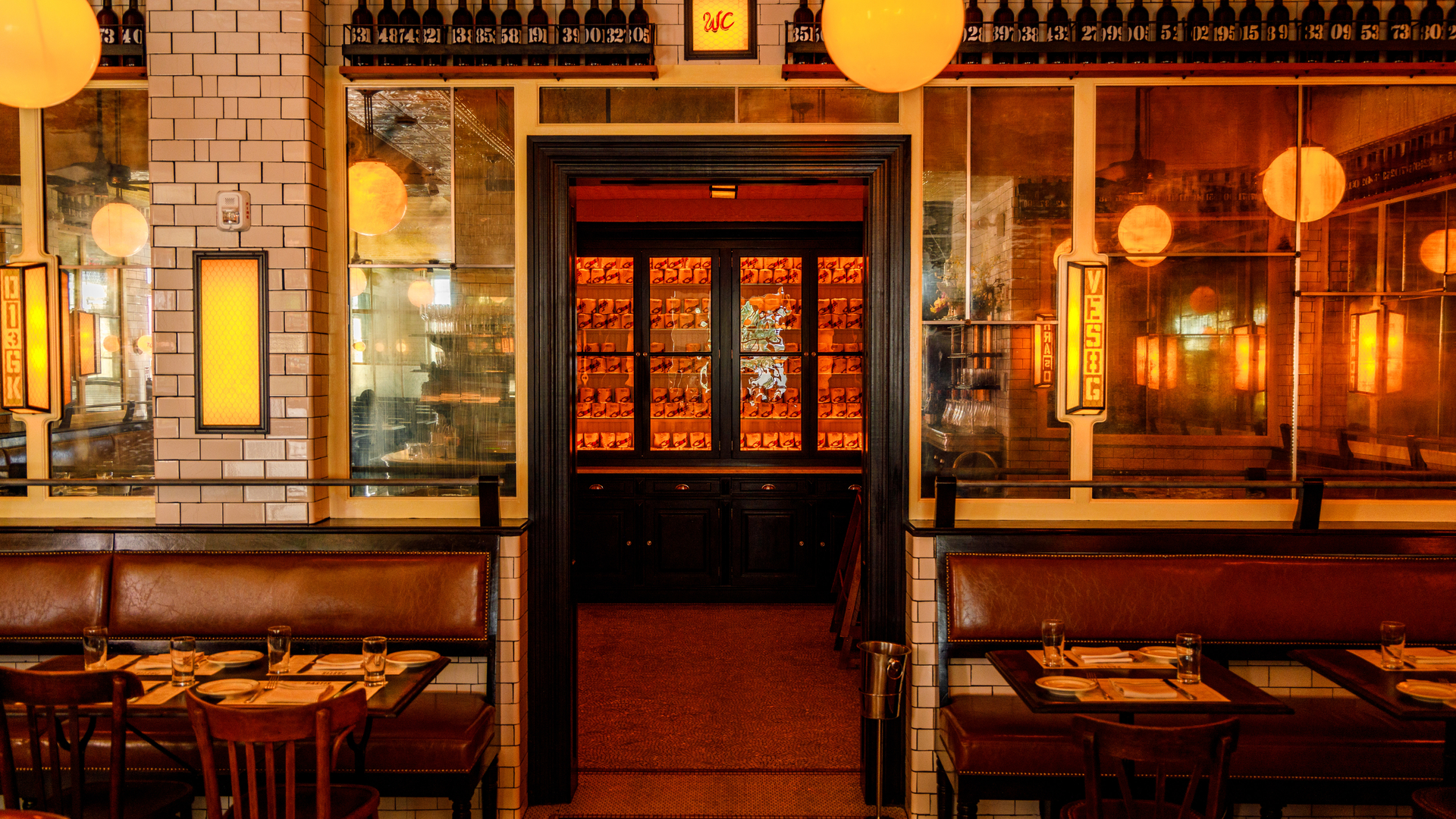 Vintage-style restaurant with retro decor, tables set for dining, brass ceiling fans, white subway tiles, and framed artwork.